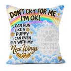 A square decorative throw pillow with a printed pet memorial design. The design features a bright blue sky with white clouds, a rainbow, gold hearts, and the text 'DON'T CRY FOR ME I'M OK! I CAN RUN LIKE A PUPPY I CAN EVEN FLY WITH My New Wings' along with a gray placeholder paw print and 'YOUR PET PHOTO HERE'.