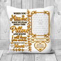 A square white pet memorial pillow with a gold and black printed design, featuring a photo frame placeholder, the text 'When you miss me have no fear hold this pillow and know I will keep you warm forever in your heart,' and a heart-shaped area that reads 'Forever loved forever missed Always remembered.' The pillow is shown against a light gray wood plank background.