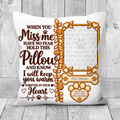 A square white pet memorial pillow with a warm brown and gold printed design, displayed on a light gray wood plank background. The design features a photo frame placeholder, paw prints, and comforting text that reads 'WHEN YOU Miss me HAVE NO FEAR HOLD THIS Pillow AND KNOW I will keep you warm FOREVER IN YOUR Heart'.