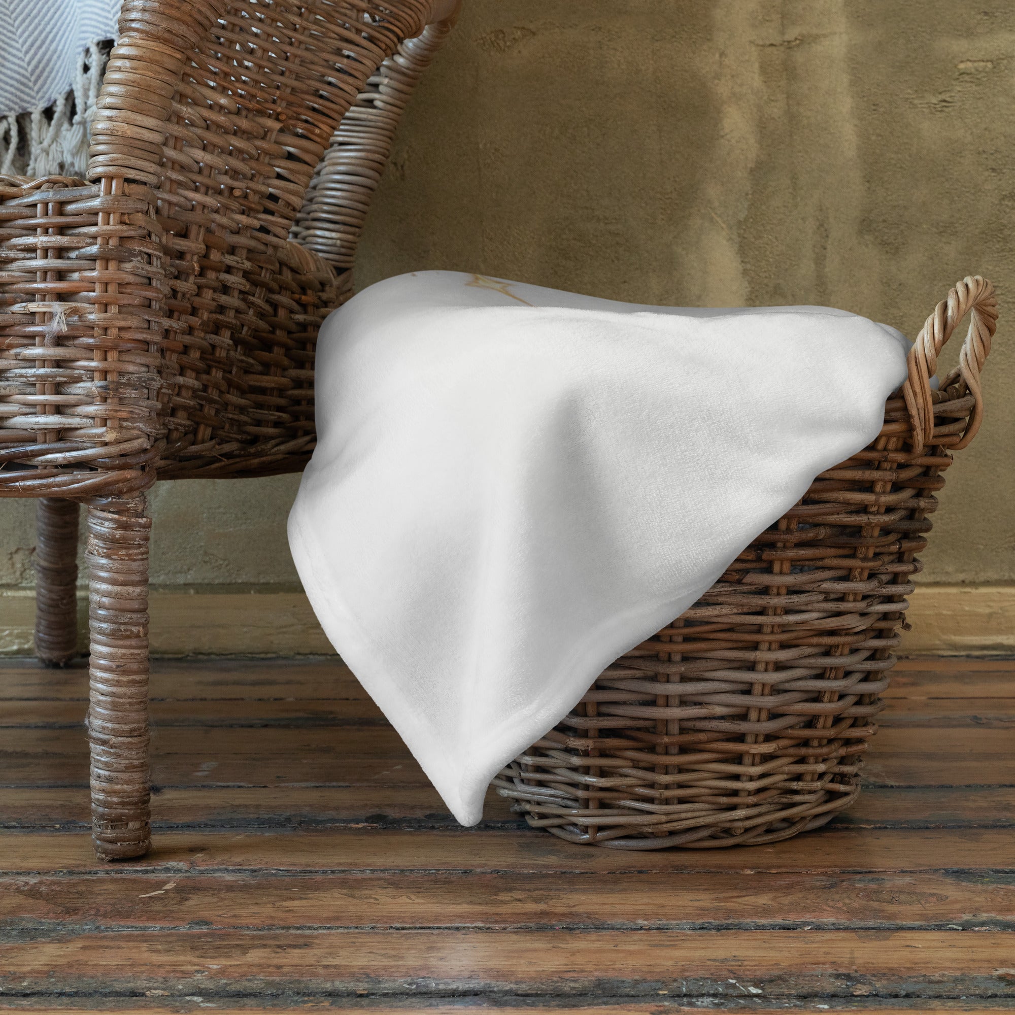 White polka dot blanket draped over a wicker basket on a wooden floor.